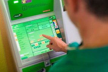 Giocatore fa una scommessa ippica al distributore automatico. 